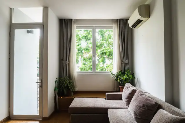 Living room with a ductless wall unit mounted high above a grey sofa