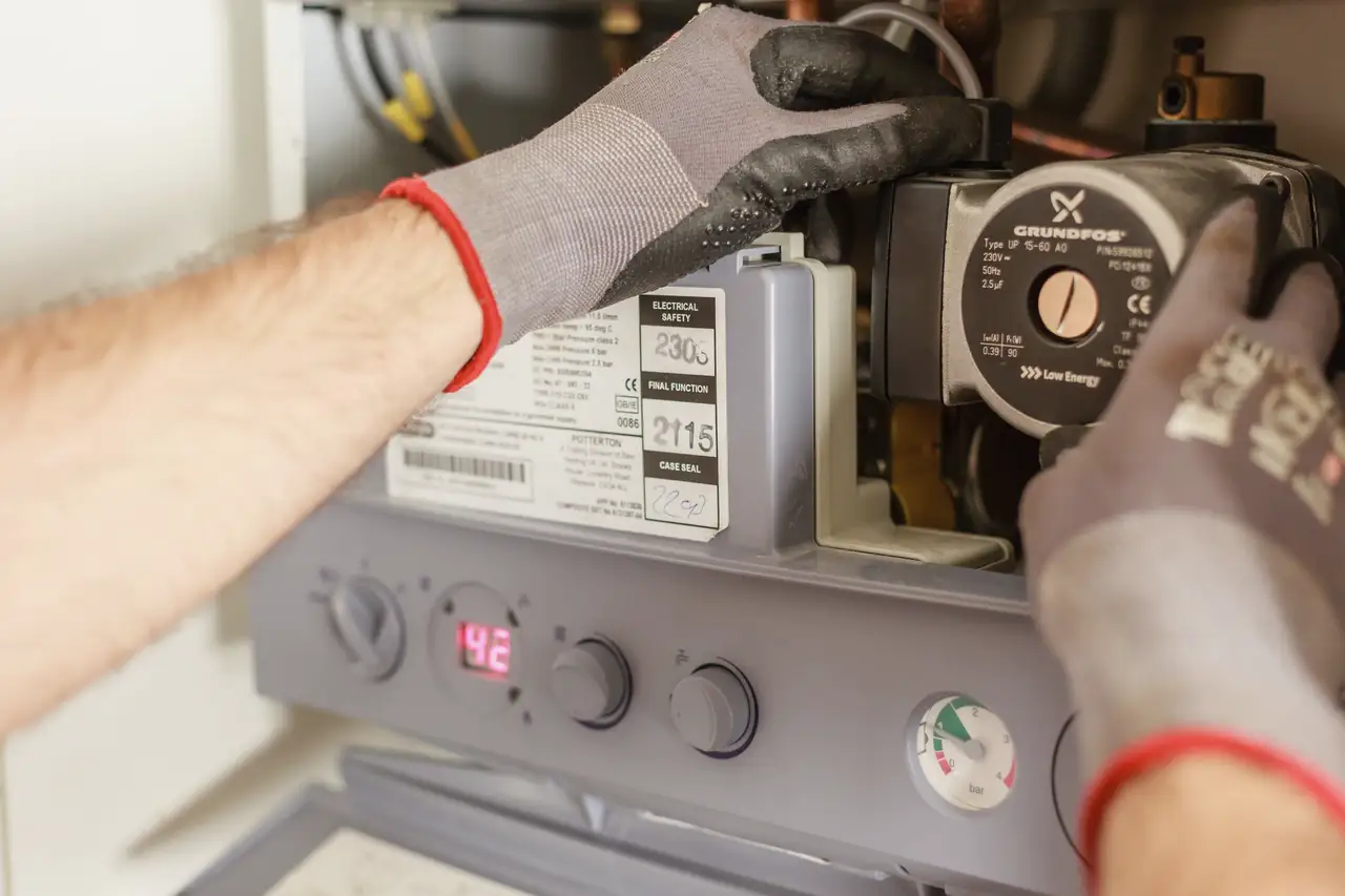 Technician's gloved hands testing the control board of a heating unit