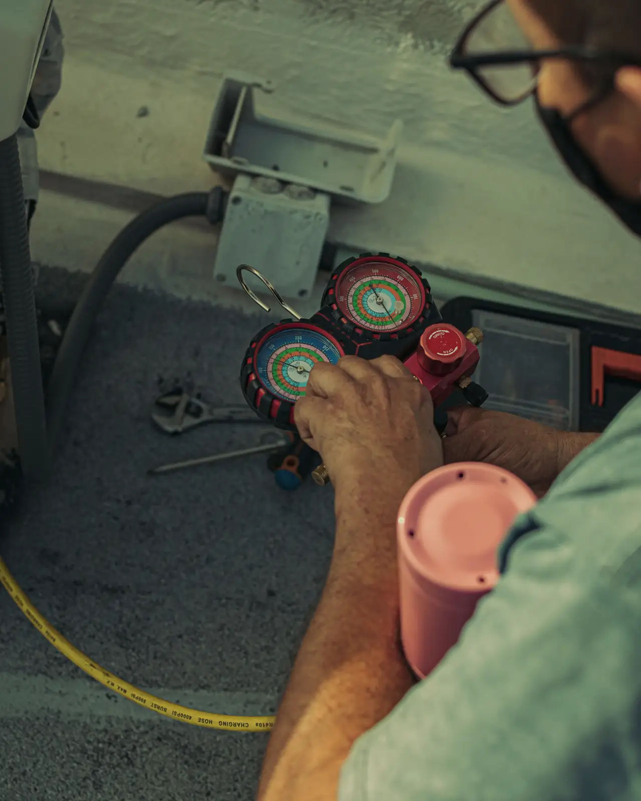 Technician reading refrigerant pressure gauges on an outdoor unit