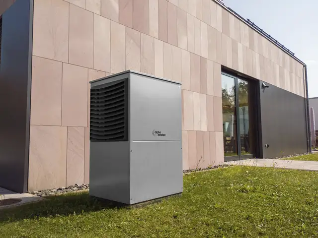 Modern outdoor heat pump unit on a lawn beside a clad building