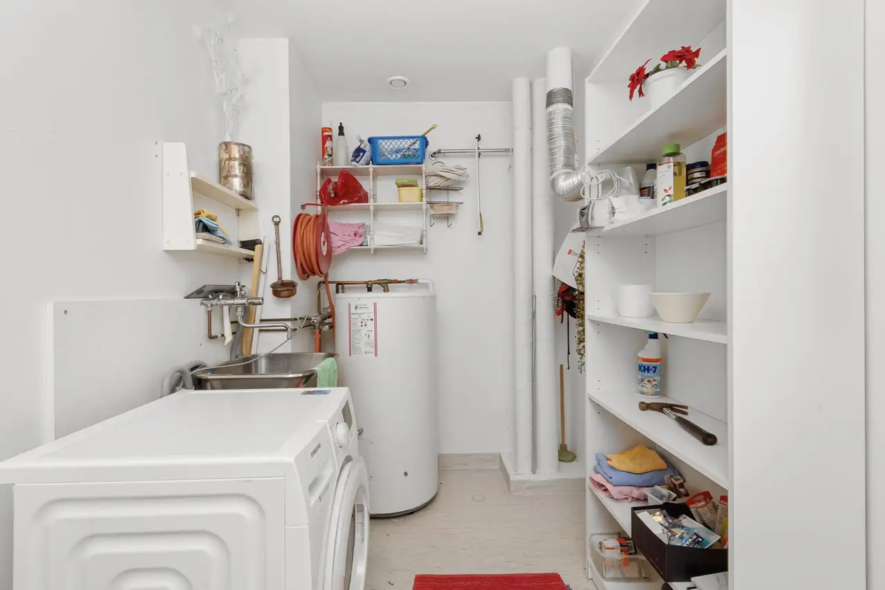 Tidy laundry room with a white tank water heater beside shelves